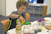 image of Miles Higgins, 12, a Boston resident and seventh-grader Clarence R. Edwards Middle School, adds lemon juice to a red cabbage juice solution during a -Science and Cooking for Kids- lab session