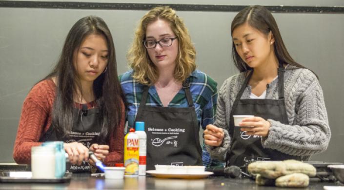 image of students using a soufflé torch to give a golden brown color to chocolate chip cookies baked in the microwave